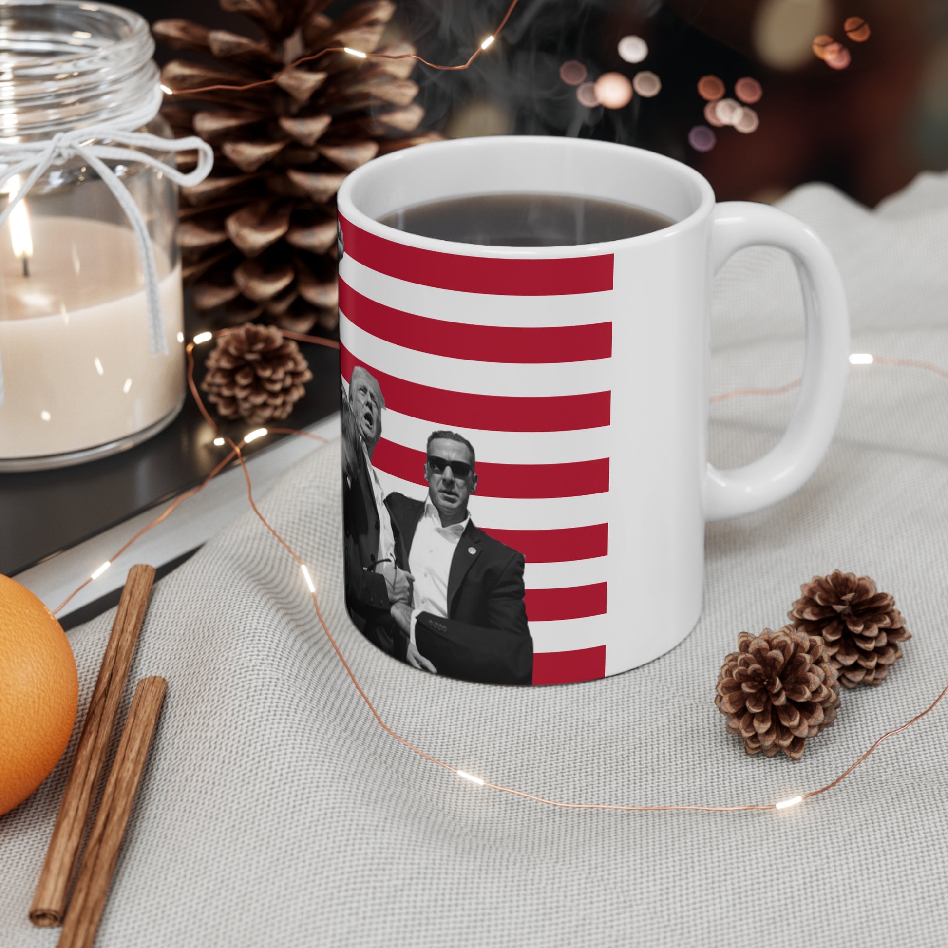 White base mug with former president Donald Trump fist bumping with an USA flag background on a table with a holiday themed background and steaming hot coffee in the mug